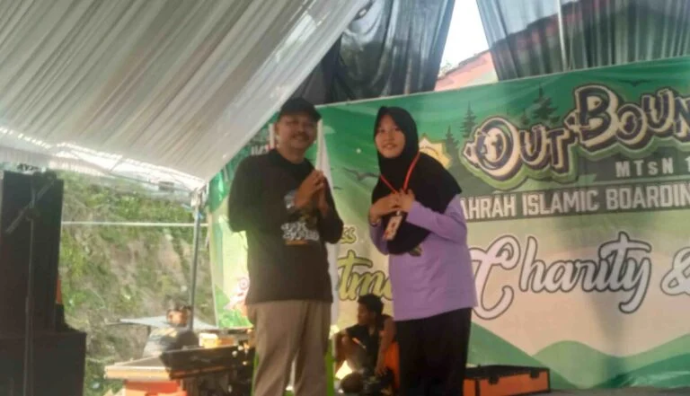 Kepala Kemenag Pati, Ahmad Syaiku, simbolis mengalungkan tanda peserta outbond kepada salah satu siswi Boarding School Az-Zahra MTsN 1 Pati