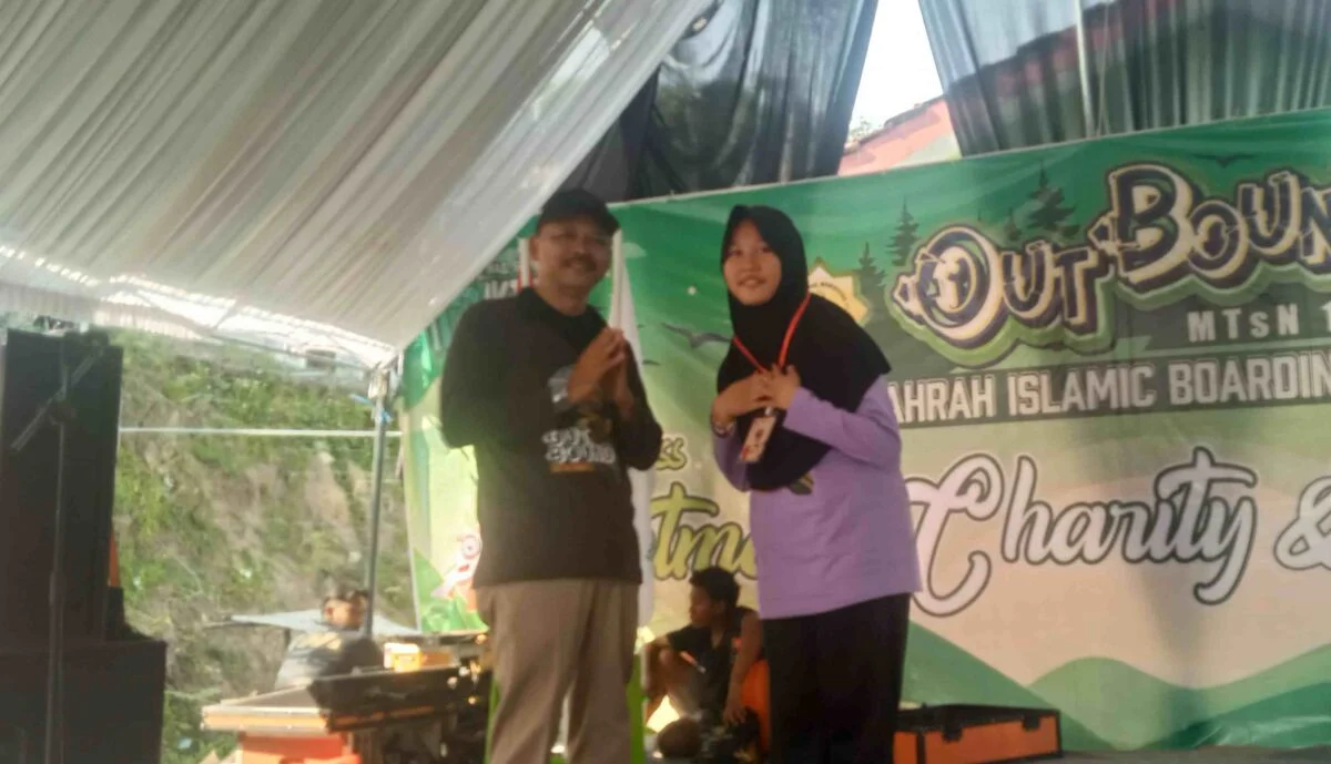 Kepala Kemenag Pati, Ahmad Syaiku, simbolis mengalungkan tanda peserta outbond kepada salah satu siswi Boarding School Az-Zahra MTsN 1 Pati